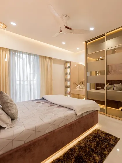 A stunning bedroom featuring a large sliding wardrobe with a frosted glass and gold design. The room is designed with a cohesive color palette, including a velvet bed and matching curtains.
