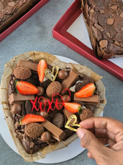 Decorating a heart-shaped brownie with cute "XOXO" and heart toppers. These little details make each gift box feel extra special.
