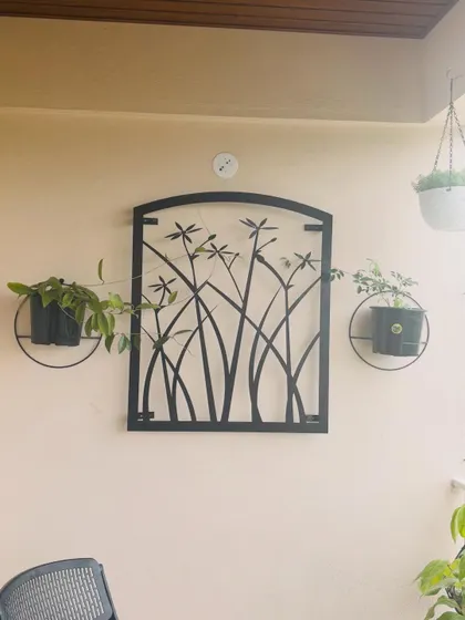 This creative wall decor combines metal art with live plants. The simple black planters with trailing plants frame the dragonfly art, turning the wall into a unique and beautiful feature.