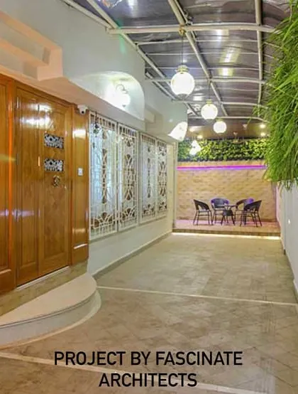 The entrance of a Vashi row house, featuring a covered walkway with lush greenery and elegant lighting. This design creates a grand and welcoming approach to the home.