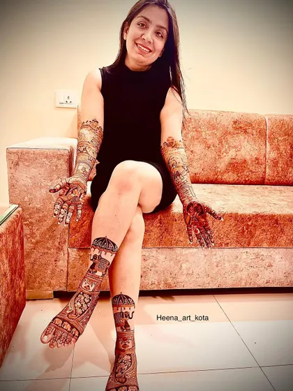 A happy bride showing her complete bridal look, with intricate designs on both her hands and feet.