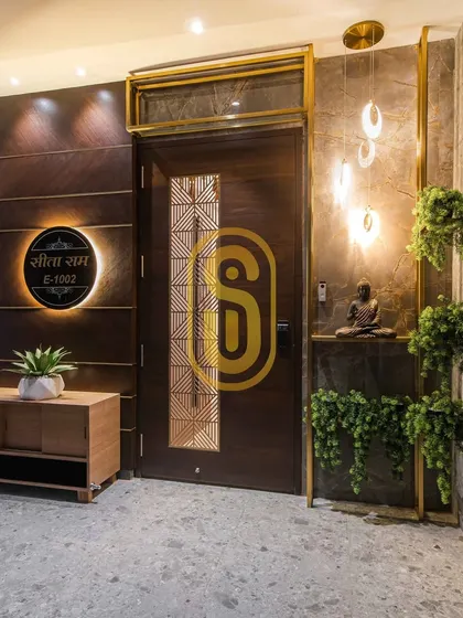 The entrance sets the tone for the entire home. We designed this welcoming foyer with a custom wooden door, an illuminated nameplate, and elegant pendant lighting, creating a memorable first impression.