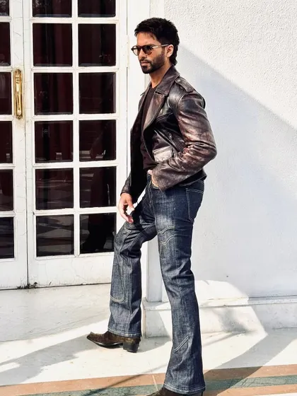 A different angle that shows off the flared cut of the jeans, adding a retro touch to this classic leather jacket look.