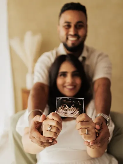 Sharing the very first picture of their baby. This couple holds up their ultrasound photo, a significant and emotional part of their maternity journey.