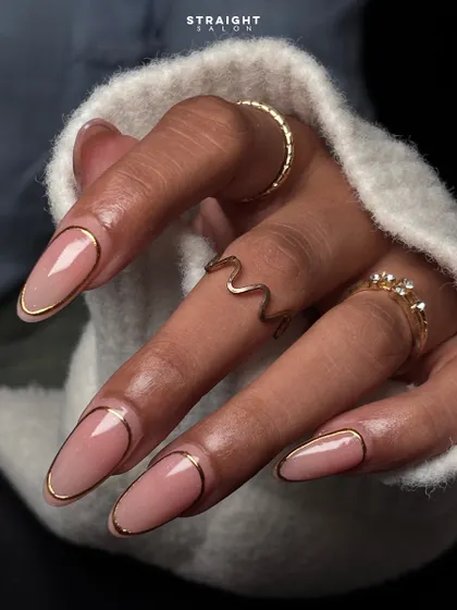 Understated elegance with a touch of gold. This minimalist design features a clean nude base on long oval nails, framed with a delicate, hand-painted gold outline for a chic and modern look.