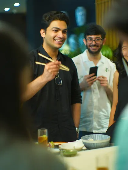 It's not just about cooking; it's about community. Participants chat and laugh while learning to use chopsticks to enjoy the sushi they've just prepared.