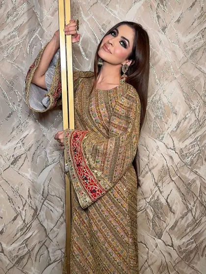 A full-length shot showcasing the complete festive look. The bold makeup complements the richly embroidered outfit, creating a look that is perfect for celebrating in style.