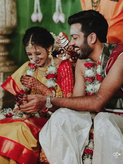 A candid moment of the couple sharing a laugh while performing a wedding ritual together.