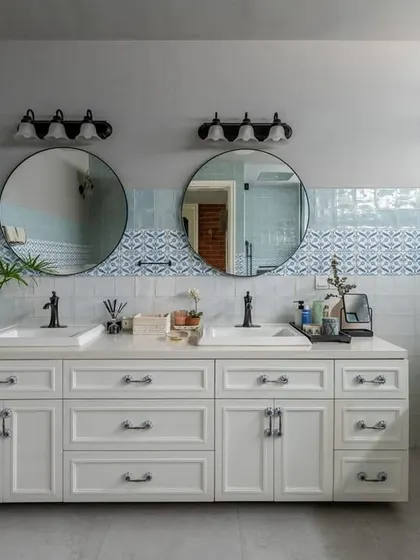 A serene, spa-like bathroom in the Dhaka residence. The double vanity, large mirrors, and a freestanding tub create a sense of luxury and calm. The blue and white patterned tiles add a touch of traditional craftsmanship.