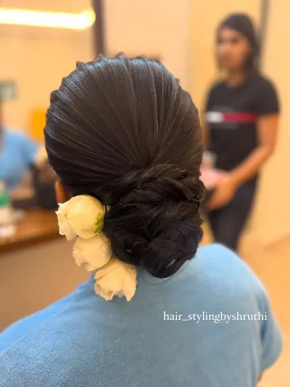 A sleek, structured updo with clean lines and a side placement of three white roses. This is a very sophisticated and modern take on the classic floral bun.