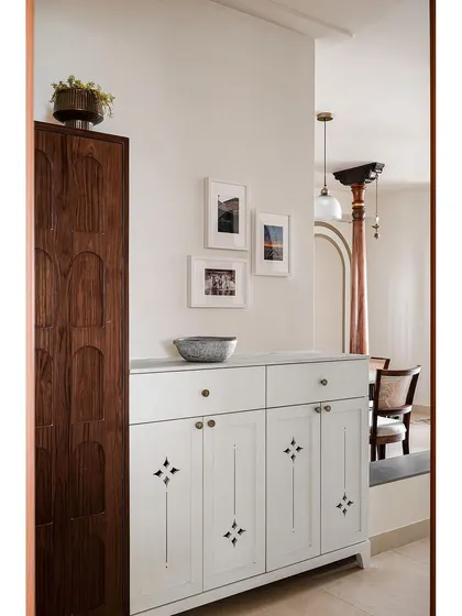 The foyer of the 'Kanasu' home sets a nostalgic tone with frames showing life in Mangalore. A vintage-style cabinet with antique handles embodies the harmony of old-world charm and contemporary functionality.
