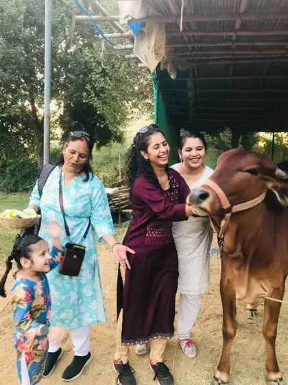 A multi-generational group of women and a young child smiling as they pet one of our gentle cows.