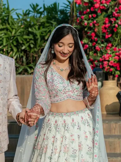 A sweet moment during the Varmala. Her floral pastel lehenga is perfect for a day function, and the makeup is light, fresh, and pretty.