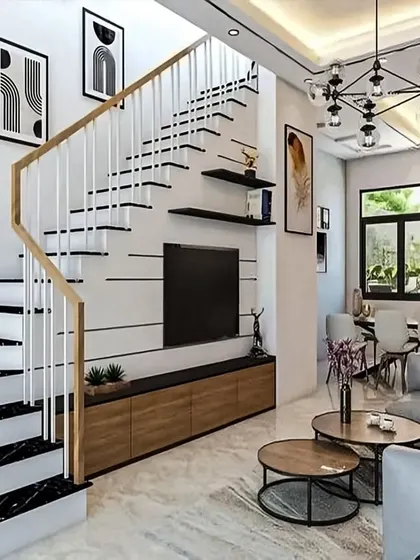 A minimalist TV unit integrated into the wall beneath a modern staircase. The simple, clean lines of the console ensure that the focus remains on the open-plan living space and architectural elements.