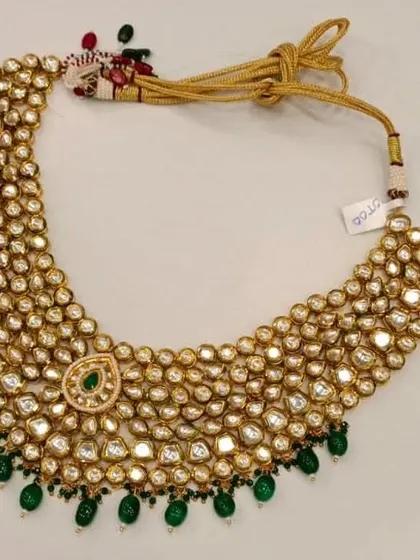 This wide Kundan choker is a true statement piece. The dense arrangement of stones and the delicate green bead drops create a look of pure opulence, perfect for a bride.