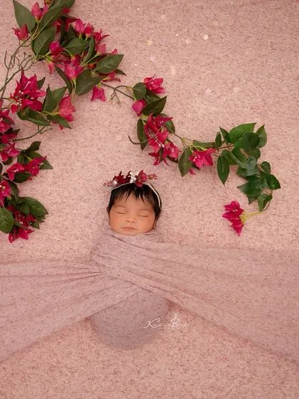 Such a doll. This baby is swaddled in a soft pink wrap, with beautiful bougainvillea flowers adding a pop of vibrant color to the simple setup.