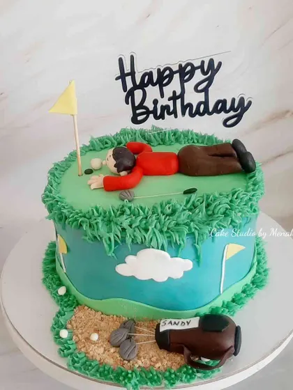 A fun golf themed cake showing a golfer lying on the green to line up his shot. A playful design for someone who loves the sport.