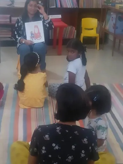 A young girl turns to look at the camera, but her friends remain focused on the story. Our sessions create a captivating environment that minimizes distractions.