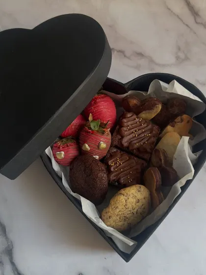 Gifting should be an experience. My heart-shaped Valentine's gift box is filled with an assortment of treats like chocolate-covered strawberries, fudgy brownies, and gourmet cookies.