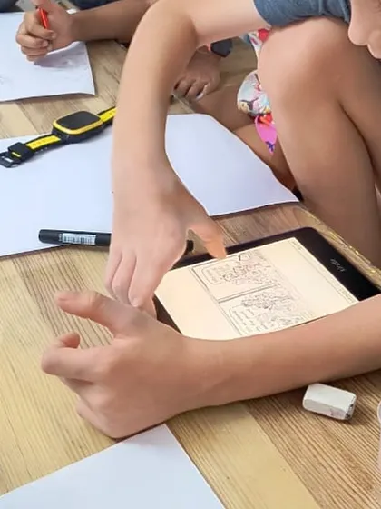 Using a tablet for reference, a student studies the details for his drawing. We integrate technology thoughtfully to support traditional art skills and provide inspiration.