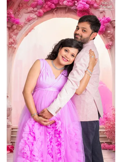 A sweet couple's portrait within our pink floral arch setup. The partner's embrace adds a layer of warmth and love to the whimsical scene.