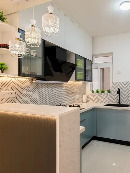 Another angle of the pastel blue and white kitchen, highlighting the breakfast counter and stylish pendant lights that create a perfect spot for casual meals.