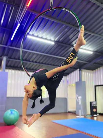 Your talent is a gift. This young aerialist showcases her skills with a beautiful split pose on the hoop, a result of her hard work and our supportive coaching.