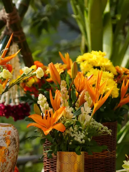 A vibrant bouquet of orange lilies and yellow flowers in a wicker basket, part of the sunny and cheerful Haldi decor.