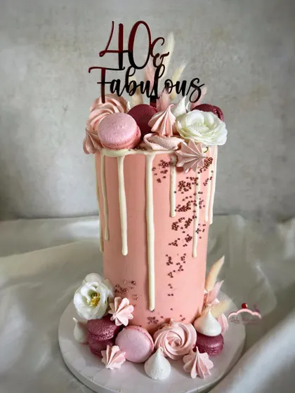 A rose gold beauty for a 40th birthday. This extra-tall 10-inch cake is adorned with a white chocolate drip, macarons, meringues, and flowers for a truly fabulous look.