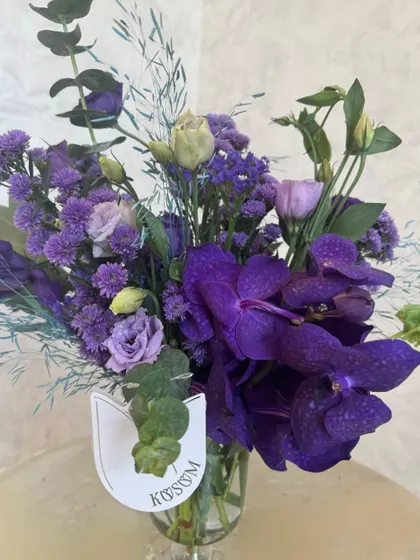 It's a Vanda orchid soirée. This simple yet stunning arrangement focuses on the deep, rich purple of the Vanda orchid, a truly exotic and luxurious bloom.
