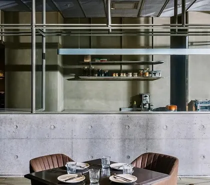 At the Evoo restaurant in Gurugram, the open kitchen is framed as a stage for culinary performance. The structure of exposed concrete and steel defines the space, creating an industrial aesthetic that complements the modern Italian dining experience.