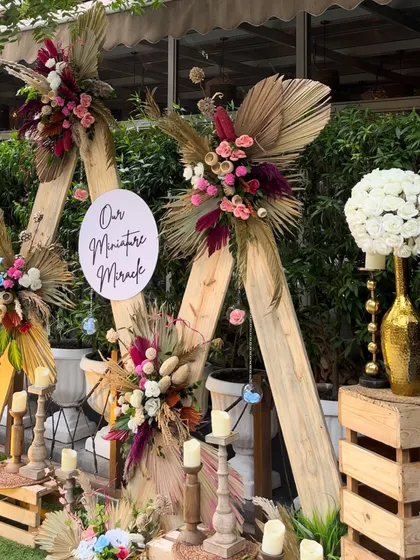 Another angle of the boho-chic baby shower backdrop, showing the layered look of the wooden crates, candles, and floral arrangements.