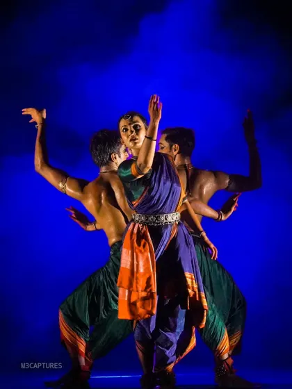 A swirling group formation from 'Nagamandala'. The choreography here uses circular patterns and contrasting movements to create a visually rich and complex scene.