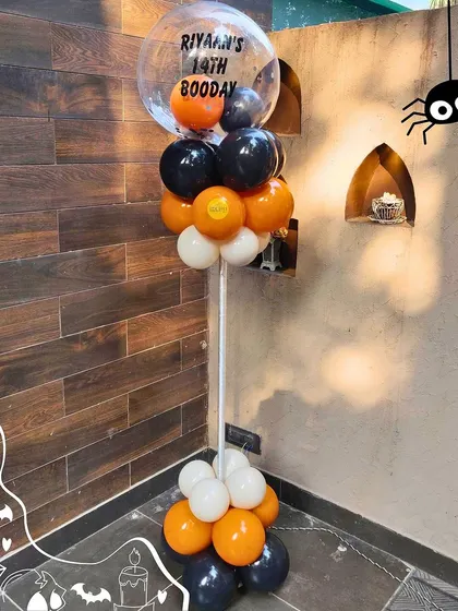 A custom balloon pillar for the Halloween party, featuring a personalized bubble balloon wishing Riyaan a happy "Booday." It's these little touches that make a theme complete.