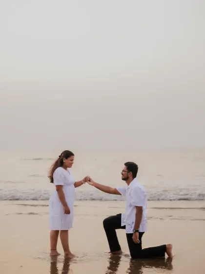 A romantic proposal-style photo on the beach, with the groom-to-be on one knee. This is a beautiful pose to include in a pre-wedding series.