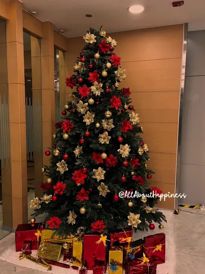 A full shot of the classic red and gold themed Christmas tree, complete with beautifully wrapped gift boxes at the base.