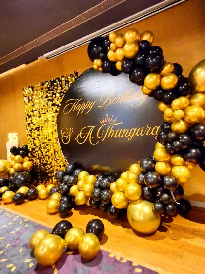 A different angle of the black and gold 95th birthday setup, showing the sweep of the balloon garland around the custom sign.