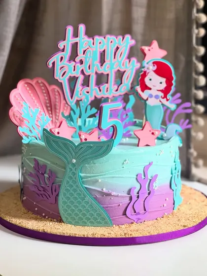 No fondant, no problem! This magical mermaid cake for a 5th birthday uses custom paper toppers and dreamy buttercream colors to create an enchanting under-the-sea theme.