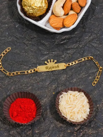 This gold-plated chain rakhi features a nameplate with a small crown charm on top.