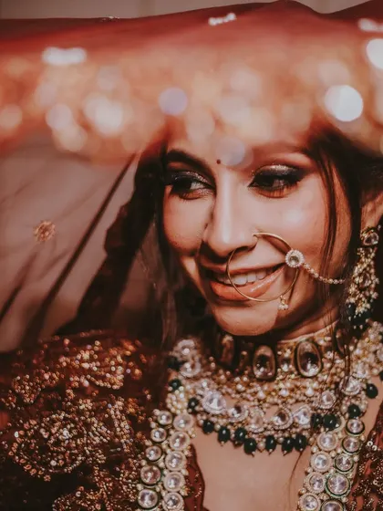 A beautiful, smiling bride captured through her veil, with bokeh lights in the background adding a magical touch.