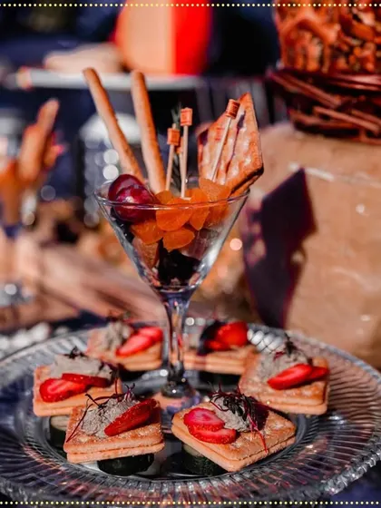 A close-up of our artfully arranged appetizers, including fruit and cracker cups in martini glasses and strawberry-topped canapés, perfect for a lavish wedding.