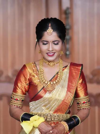 A full-length view of a bride's muhurtham attire. The saree is draped to perfection, with the pleats falling evenly and the Oddiyanam sitting just right, completing this classic bridal look.