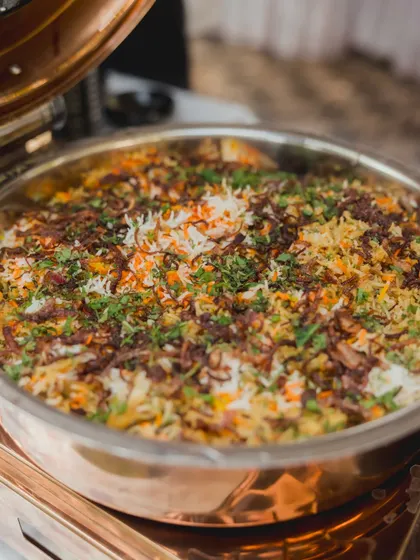 A large copper pot filled with my fragrant traditional Biryani. Topped with crispy fried onions and fresh herbs, it's a timeless classic that's always a centerpiece of the main course.