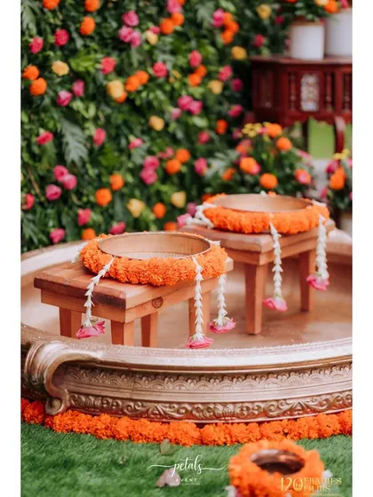 Detail shot of the traditional wooden stools adorned with marigold garlands, ready for the Haldi ritual.