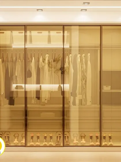 A stunning walk-in closet with gold-tinted glass sliding doors and internal lighting. This design allows you to see your collection while keeping it protected and organized.