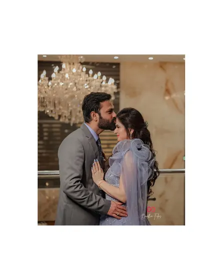 A tender forehead kiss under a brilliant chandelier, this photo epitomizes the elegance and romance of a formal engagement.