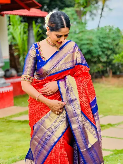 A close-up of me in the red and blue saree, showing the intricate gold weaving and the custom-embroidered blue blouse.