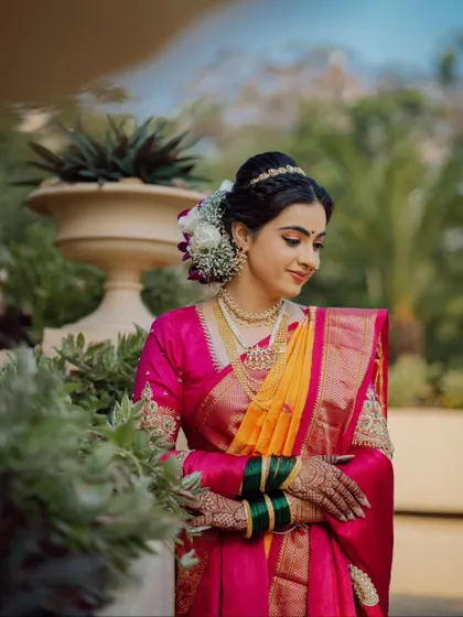 A beautiful portrait of a Maharashtrian bride in her vibrant navari sari, surrounded by lush greenery.