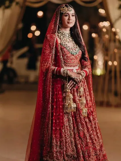 A full-length portrait of the bride in her stunning red Tarun Tahiliani lehenga, the epitome of classic bridal elegance.