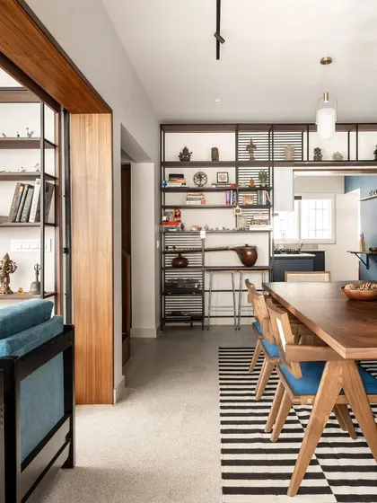 The dining room is the heart of the Keepsake home, featuring a large 8-seater table that encourages gathering. It is surrounded by open shelves displaying the client's artifacts, blending life, travel, and design into a single, cohesive narrative.
